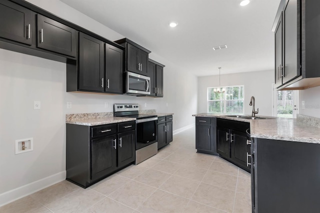 kitchen with light tile patterned flooring, appliances with stainless steel finishes, pendant lighting, sink, and light stone countertops