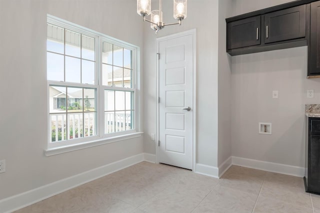 laundry room featuring cabinets, light tile patterned flooring, washer hookup, and a notable chandelier