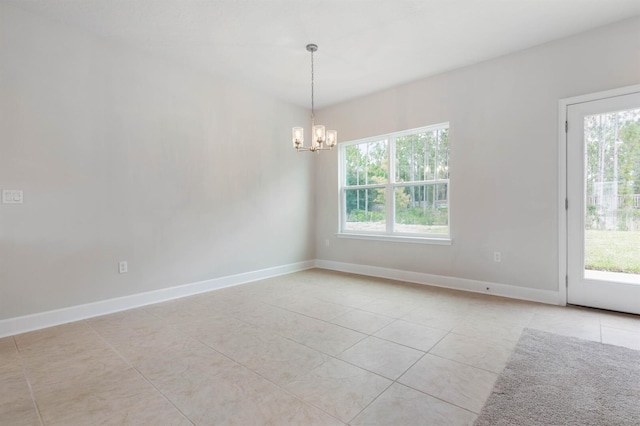 tiled spare room featuring a chandelier