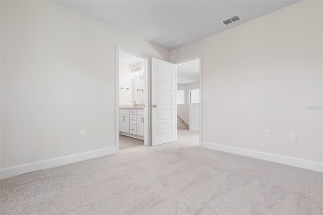 unfurnished bedroom with baseboards, visible vents, ensuite bathroom, and light carpet