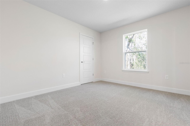 spare room with light carpet and baseboards