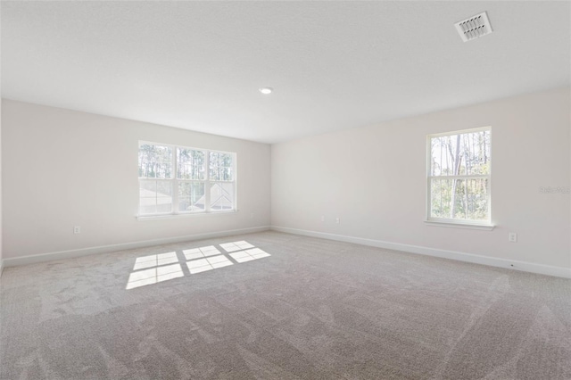 spare room featuring plenty of natural light, baseboards, visible vents, and carpet floors