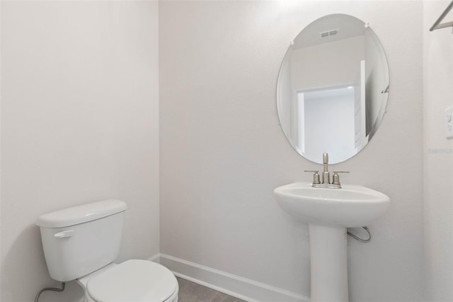 bathroom featuring a sink, baseboards, toilet, and tile patterned floors