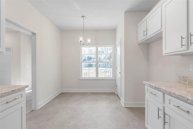 kitchen with baseboards, an inviting chandelier, hanging light fixtures, and white cabinetry