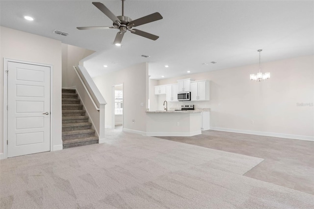 unfurnished living room with visible vents, ceiling fan with notable chandelier, recessed lighting, stairway, and baseboards