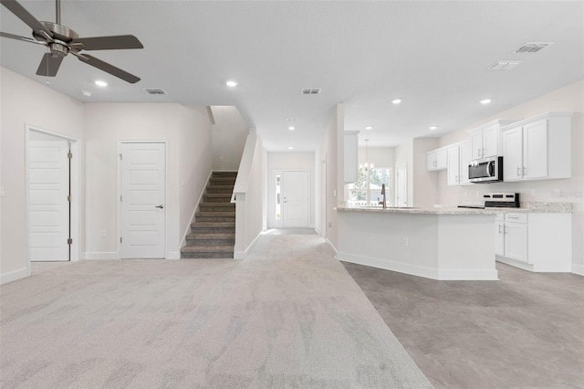 unfurnished living room with recessed lighting, visible vents, ceiling fan with notable chandelier, and baseboards