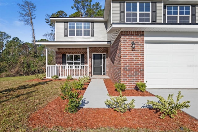 doorway to property with a garage, brick siding, covered porch, and a lawn