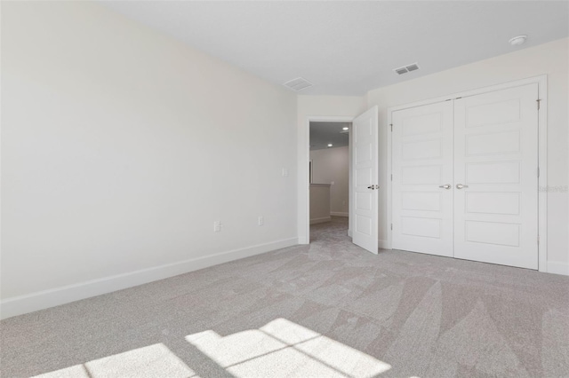 unfurnished bedroom featuring light carpet, visible vents, baseboards, and a closet