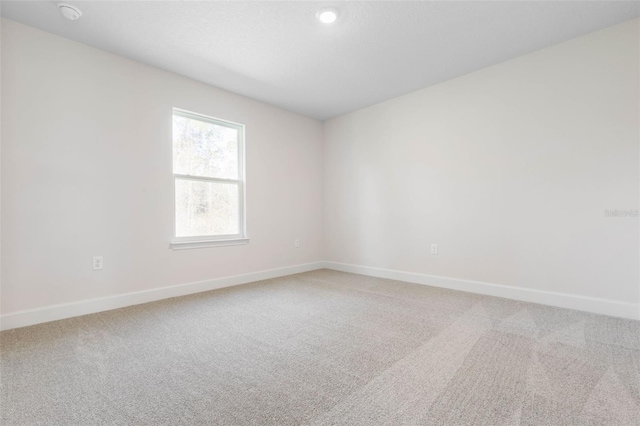 empty room with baseboards and light colored carpet