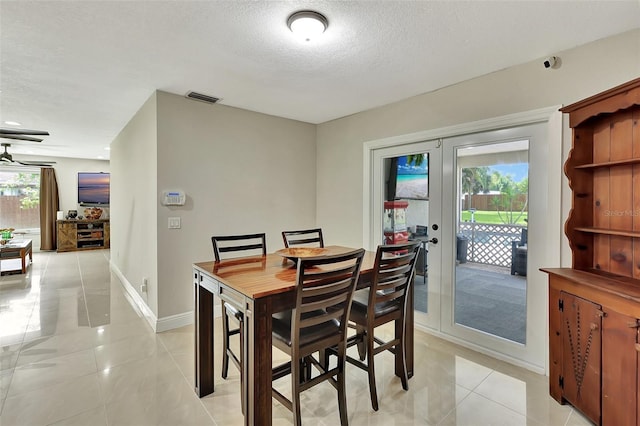 dining room with french doors, a textured ceiling, plenty of natural light, and light tile patterned floors