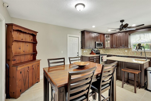 dining room with ceiling fan, a textured ceiling, and light tile patterned floors