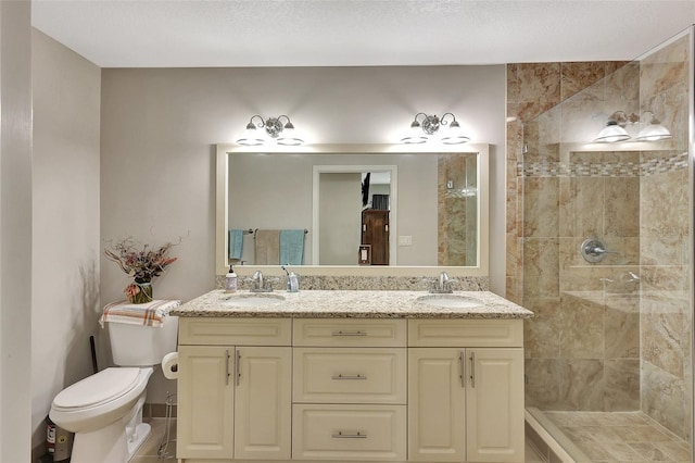 bathroom featuring a textured ceiling, a tile shower, vanity, and toilet