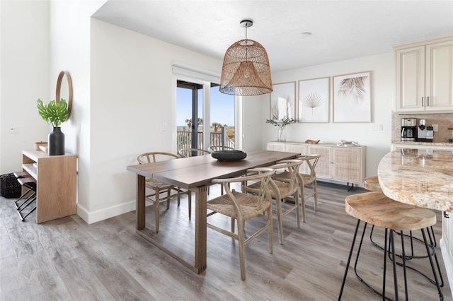 dining area featuring light wood-style flooring and baseboards