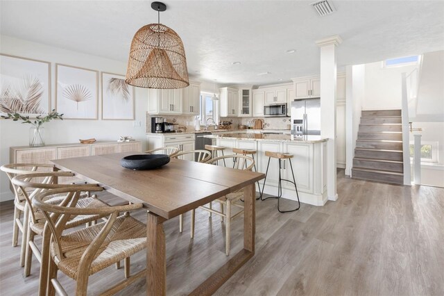 dining room featuring light hardwood / wood-style flooring and ornate columns