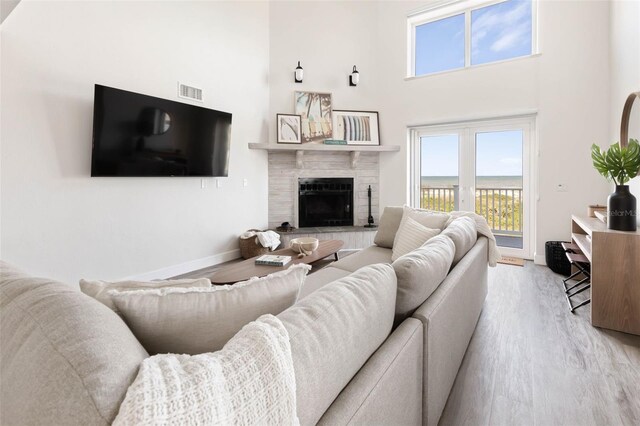 living room with a high ceiling, light wood-type flooring, and a fireplace