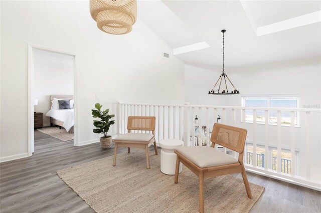 sitting room with dark wood-type flooring, an inviting chandelier, and high vaulted ceiling