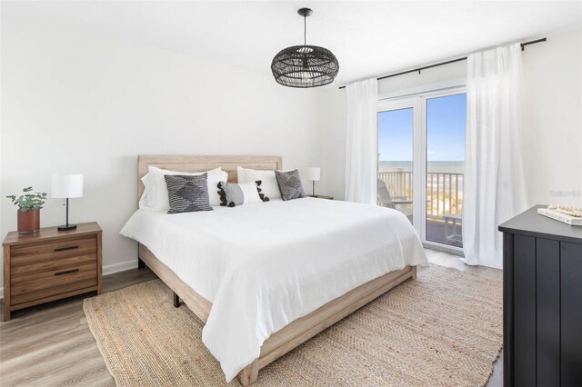 bedroom with access to exterior, a notable chandelier, and light hardwood / wood-style floors