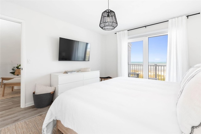 bedroom with access to outside, a notable chandelier, and light wood finished floors