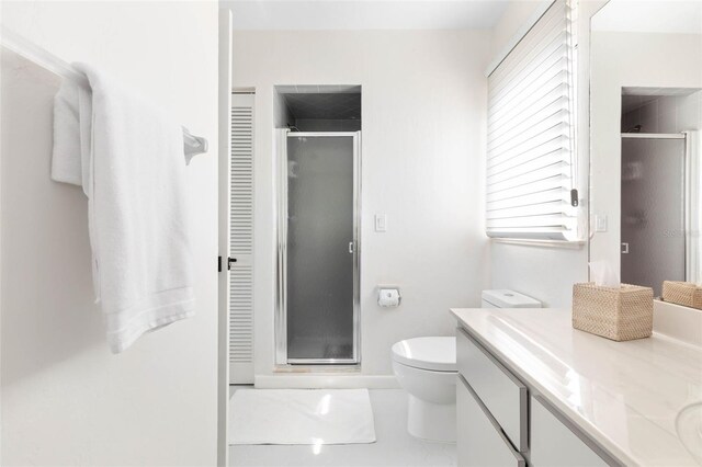 bathroom featuring vanity, toilet, and a shower with door