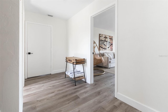 corridor with baseboards, visible vents, and light wood finished floors