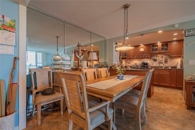 dining space with sink, light tile patterned floors, and crown molding