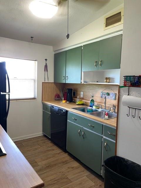 kitchen featuring black appliances, sink, backsplash, green cabinets, and dark hardwood / wood-style floors