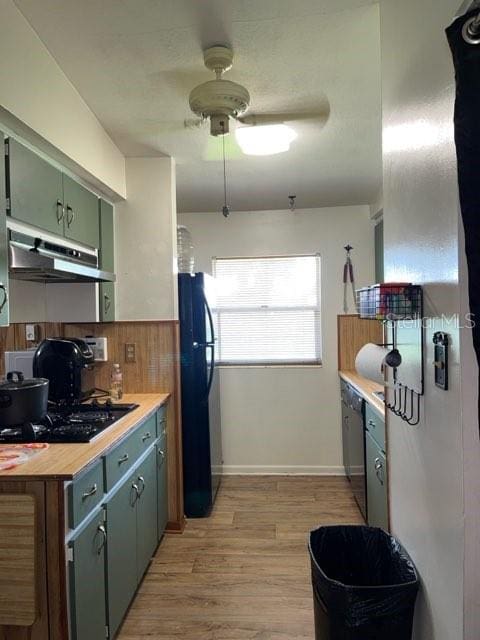 kitchen featuring ceiling fan, stainless steel dishwasher, light wood-type flooring, and black fridge