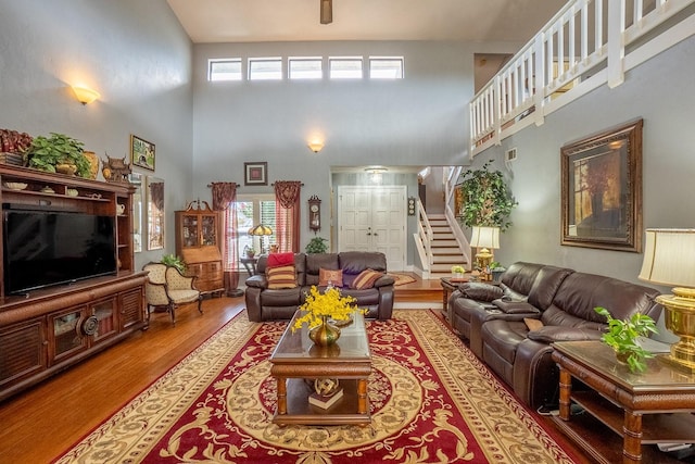 living room with stairs, a high ceiling, and wood finished floors