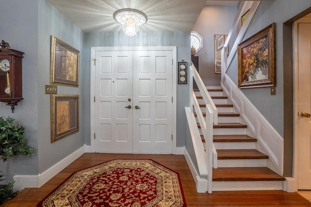 foyer with an inviting chandelier, stairs, baseboards, and wood finished floors