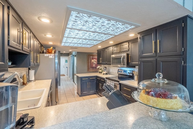 kitchen featuring light tile patterned floors, a sink, light countertops, appliances with stainless steel finishes, and tasteful backsplash