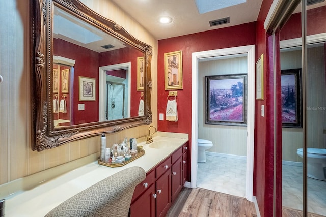 bathroom with visible vents, vanity, toilet, and wood finished floors