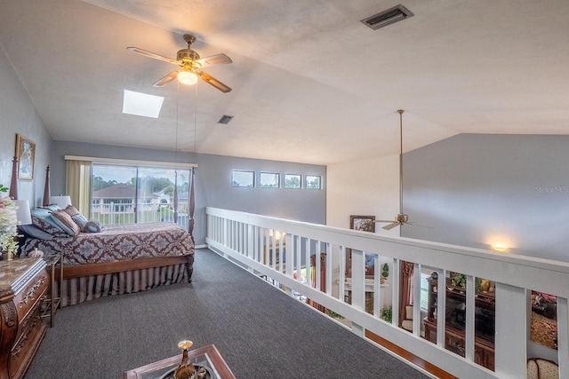 bedroom with vaulted ceiling, dark colored carpet, visible vents, and a ceiling fan