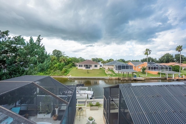 dock area featuring glass enclosure, a yard, a water view, and a residential view