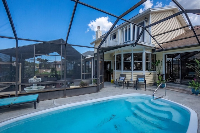 rear view of house featuring a patio area, a lanai, a sunroom, and an outdoor pool