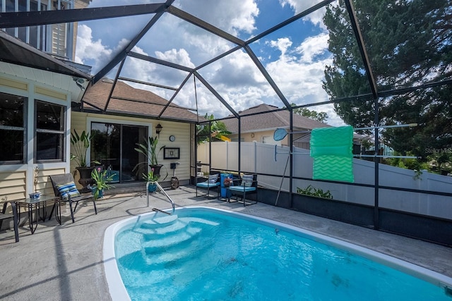 outdoor pool with glass enclosure, a patio, and fence