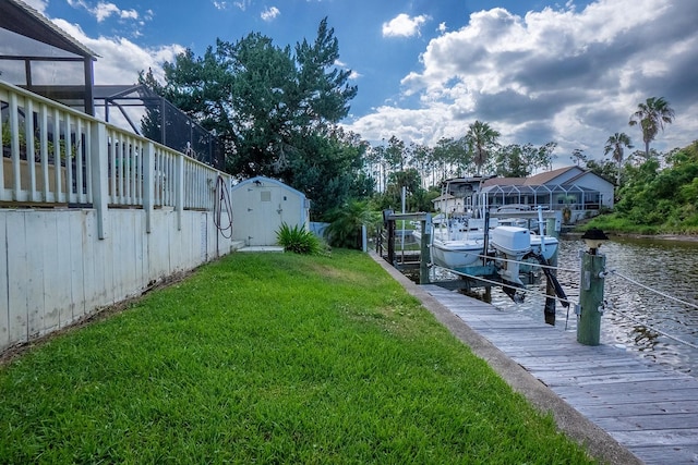 view of yard with boat lift, a lanai, a water view, a dock, and a storage unit