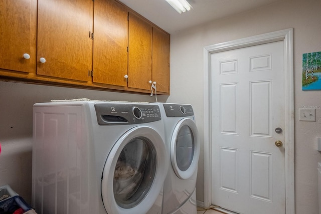 clothes washing area with washing machine and clothes dryer and cabinet space