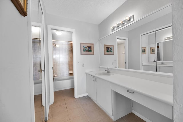 bathroom with tile patterned flooring, tiled shower / bath combo, a textured ceiling, and vanity