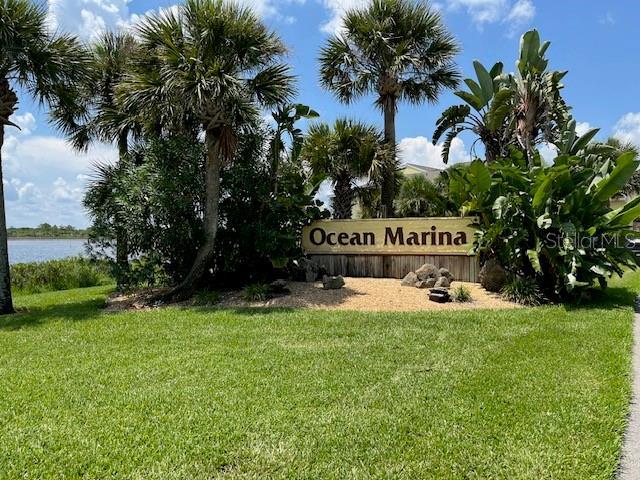 community sign with a water view and a yard