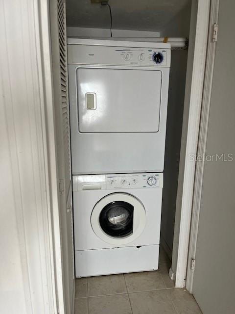 clothes washing area featuring tile patterned flooring and stacked washing maching and dryer