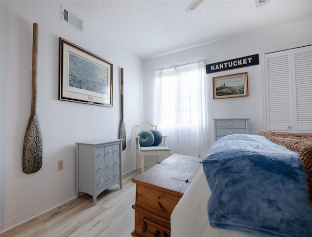 bedroom featuring ceiling fan, a closet, a textured ceiling, and light hardwood / wood-style flooring