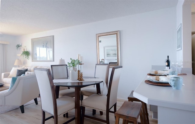 dining space featuring light hardwood / wood-style flooring and a textured ceiling