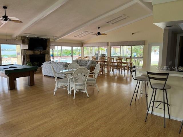 dining room with vaulted ceiling with beams, ceiling fan, a wealth of natural light, and light hardwood / wood-style flooring