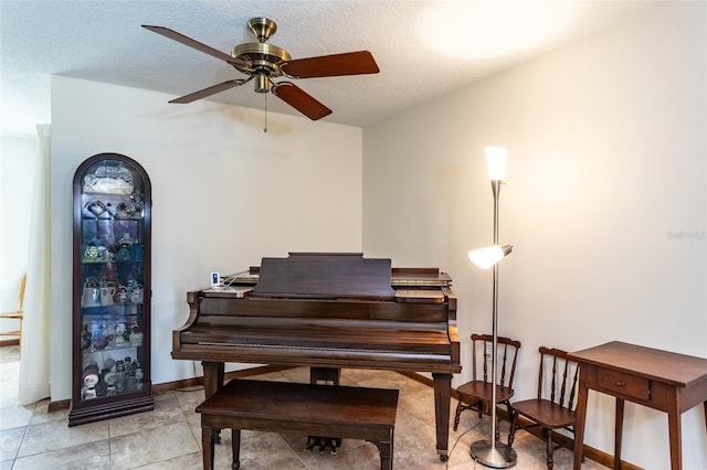 misc room with a textured ceiling, ceiling fan, and light tile patterned flooring