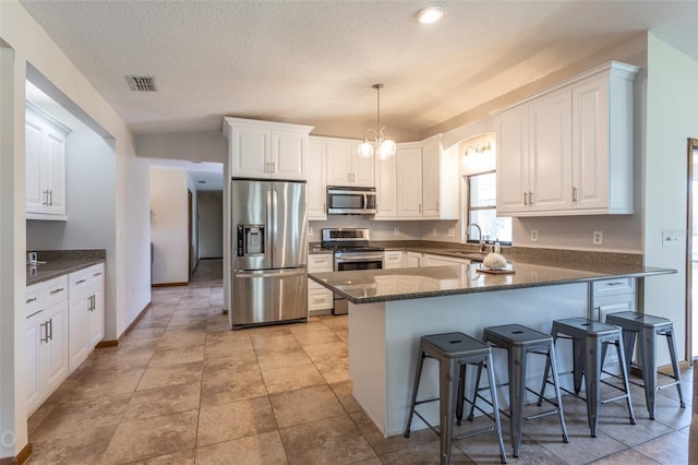 kitchen featuring stainless steel appliances, visible vents, white cabinetry, a sink, and a peninsula