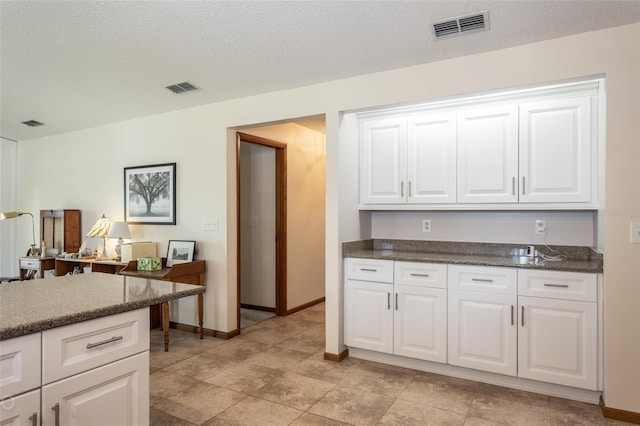 kitchen featuring white cabinetry, visible vents, and a textured ceiling