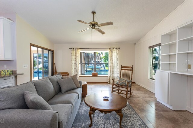 tiled living room with ceiling fan, a textured ceiling, and lofted ceiling