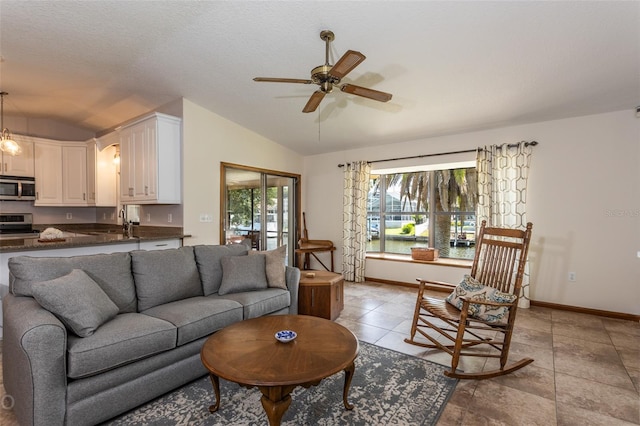 tiled living room featuring ceiling fan, vaulted ceiling, and a textured ceiling