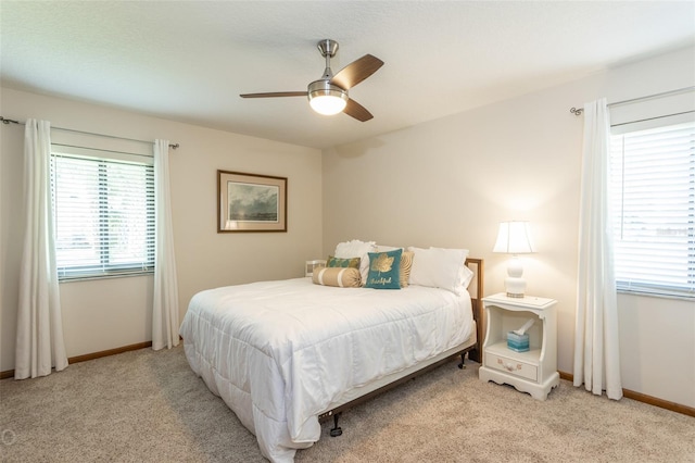 bedroom featuring a ceiling fan, multiple windows, light carpet, and baseboards