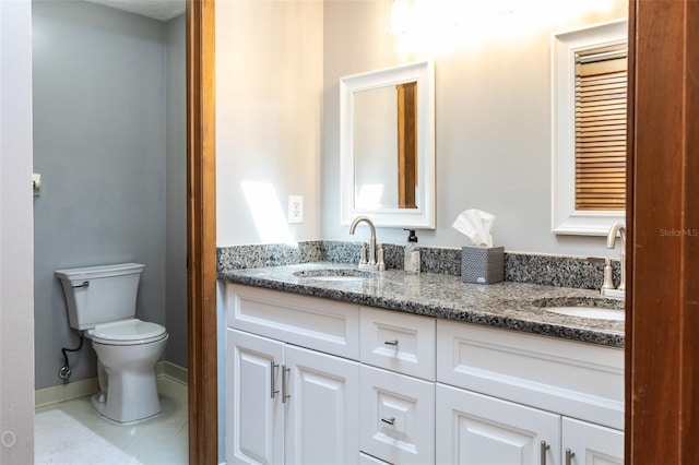 full bathroom with double vanity, a sink, toilet, and baseboards